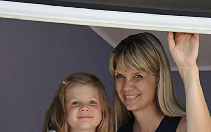 Huber Franz - Insektenschutz - Fenster - Türen – eine Frau und ihre Tochter schauen durch ein Fenster lächelnd in die Kamera