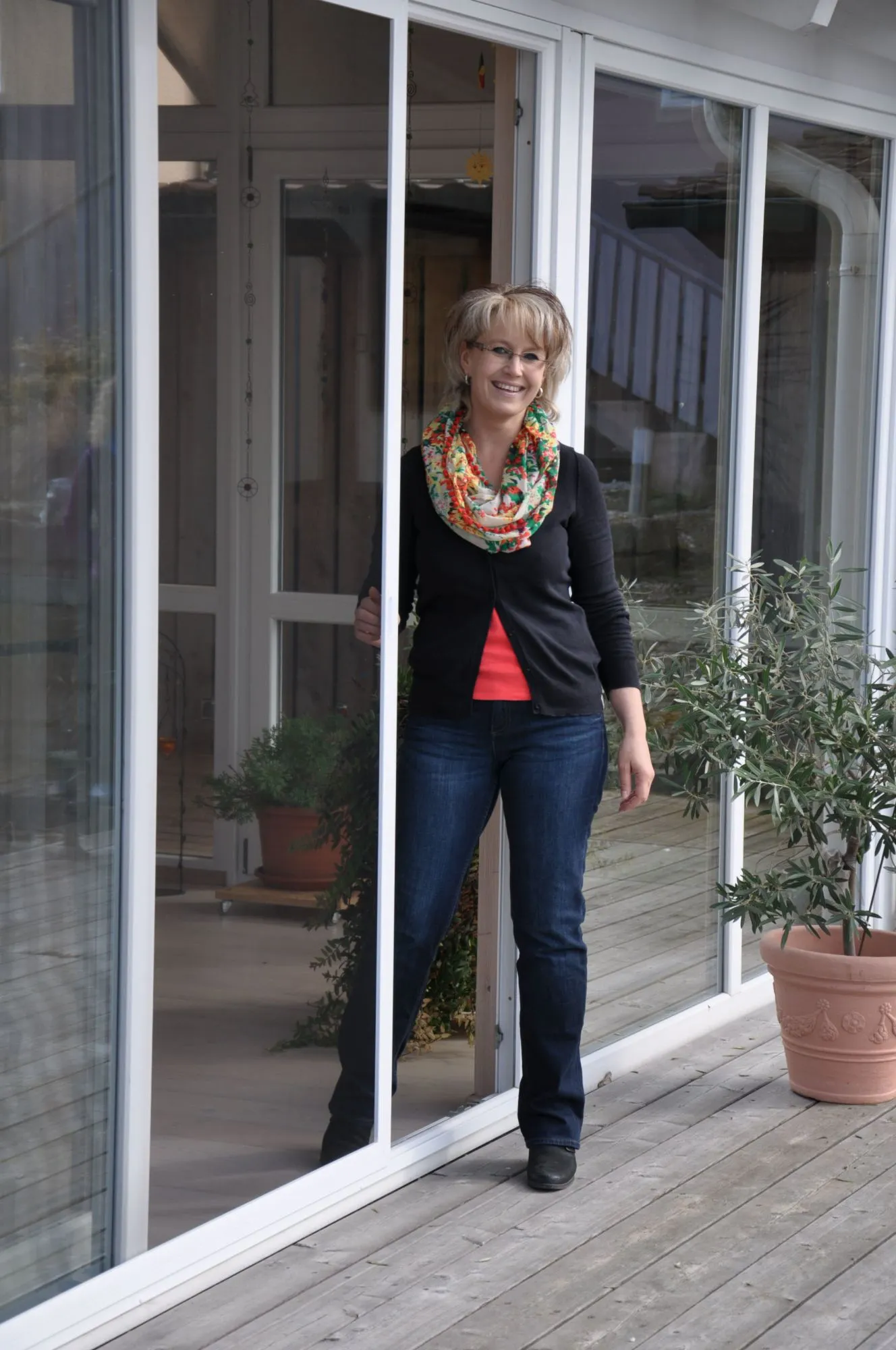 Huber Franz - Insektenschutz - Fenster - Türen – eine Frau steht lächelnd neben ihrer Schiebetür auf der Terrasse
