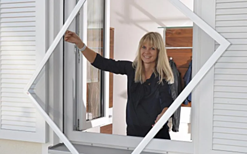 Huber Franz - Insektenschutz - Fenster - Türen – eine Frau hält einen Spannrahmen durch ein Fenster